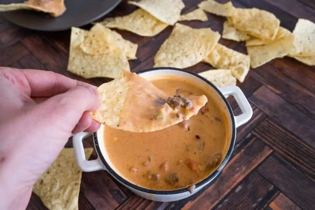 Warm and creamy queso dip with chunks of ground beef and tomatoes, perfect for scooping with tortilla chips—a must-have among the best party dips.