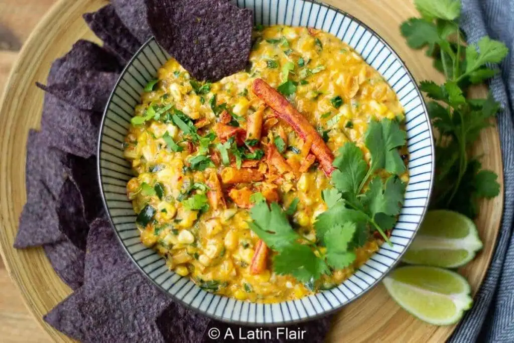 Spicy Mexican street corn dip garnished with fresh cilantro and crunchy tortilla strips, served with blue corn chips—a bold and flavorful choice for the best party dips.
