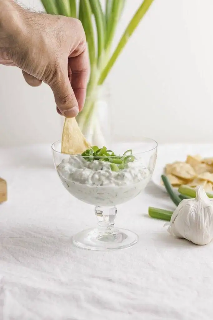 Creamy green onion dip served in a glass bowl, garnished with fresh scallions and perfect for pairing with chips—an elegant addition to the best party dips.