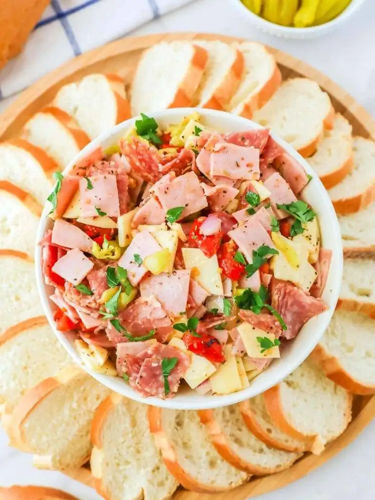 Colorful Italian sub dip filled with meats, cheeses, and peppers, served with sliced baguette—an exciting twist on the best party dips.