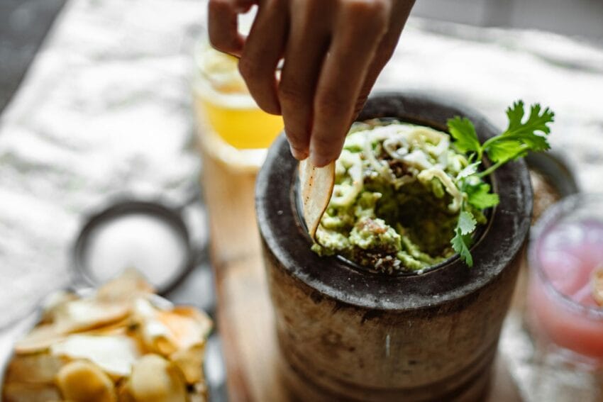 woman dipping a taco in guacamole