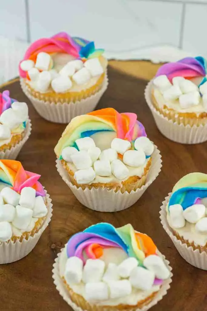 Colorful rainbow cupcakes topped with marshmallows, creating a whimsical cloud and rainbow effect, perfect for St. Patrick's Day desserts or festive celebrations.