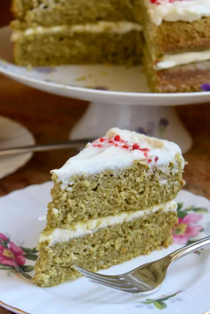 A slice of moist green pistachio cake layered with creamy frosting, served on a floral plate, perfect for St. Patrick's Day desserts or Irish-inspired celebrations.