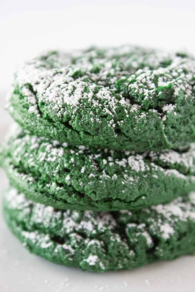 A stack of green crinkle cookies dusted with powdered sugar, perfect for festive Irish desserts or St Patrick's Day treats.