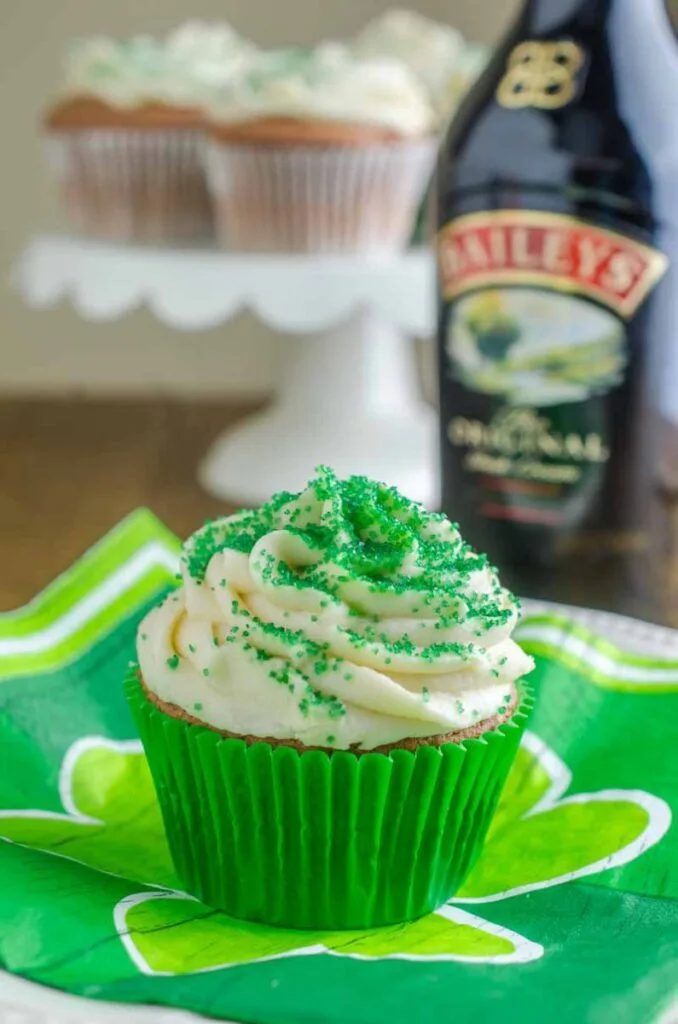 A Baileys Irish Cream cupcake with creamy frosting and green sprinkles, displayed on a shamrock-themed napkin, perfect for St. Patrick's Day desserts or festive Irish celebrations.