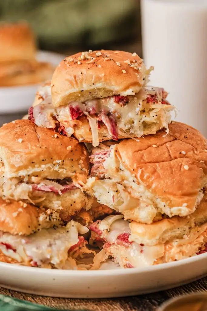 Stacked Reuben sliders packed with corned beef, tangy sauerkraut, melted Swiss cheese, and a flavorful sauce, all nestled in buttery rolls—an irresistible Irish party food!
