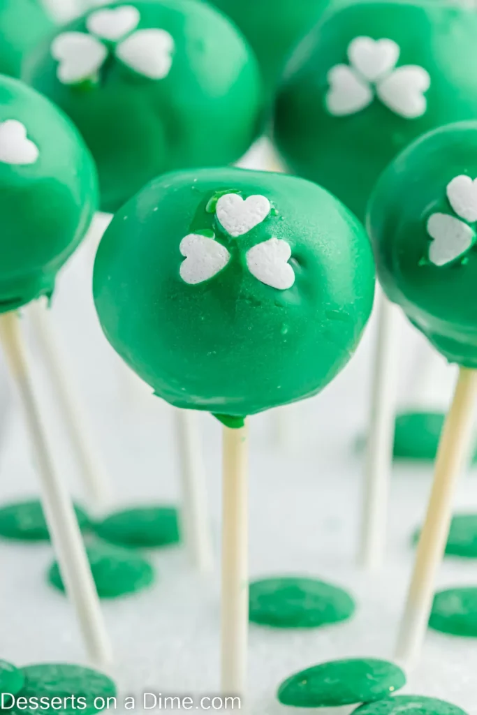 Green cake pops decorated with white shamrock-shaped sprinkles, perfect for St Patrick's Day desserts or festive Irish celebrations.