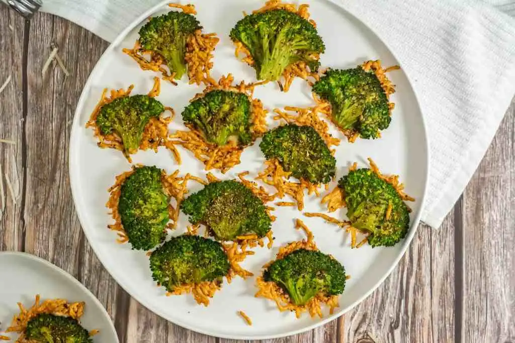 A plate of crispy roasted broccoli florets topped with shredded cheese, offering a simple yet delicious Irish party food option for a festive gathering.