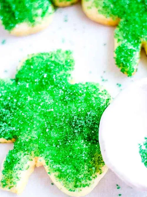 Shamrock-shaped sugar cookies coated with vibrant green sugar sprinkles, perfect for festive St Patrick's Day desserts or Irish-themed celebrations.