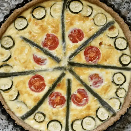 A beautifully baked farm-to-table meal featuring a summer vegetable quiche with zucchini, cherry tomatoes, and asparagus, made with fresh, locally sourced ingredients from the farmers market for a nutritious and budget-friendly dish."
