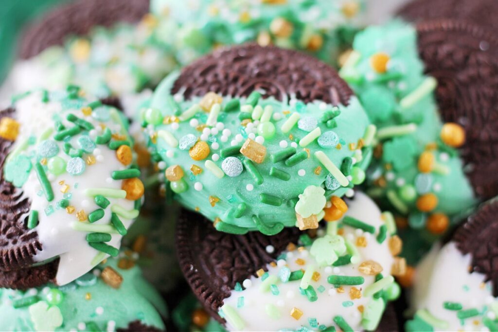 Chocolate cookies dipped in green and white chocolate, decorated with festive green, gold, and shamrock-shaped sprinkles, perfect for St Patrick's Day desserts or Irish-themed treats.