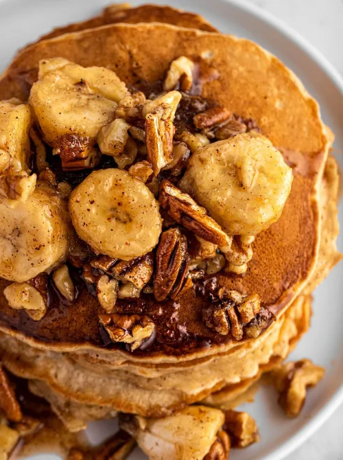 Stack of golden pancakes topped with caramelized bananas and crunchy pecans, ideal for a budget-friendly Easter brunch.