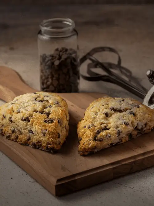 Freshly baked chocolate chip scones arranged on a wooden board, perfect for a budget-friendly Easter brunch.