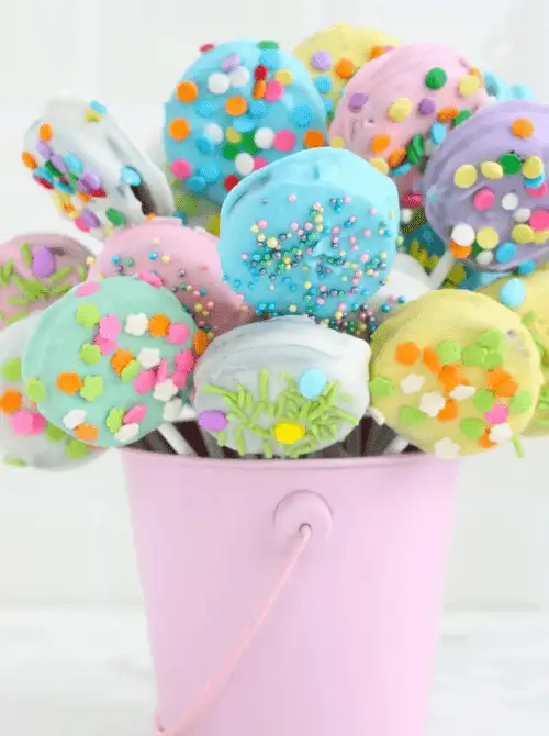 Colorful Easter chocolate-covered Oreo pops decorated with pastel sprinkles, arranged in a festive bouquet—perfect for easy Easter finger food ideas and holiday treats!