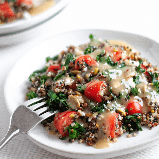 A nourishing farm to table quinoa salad, loaded with fresh kale, juicy cherry tomatoes, and crunchy seeds, all drizzled with a creamy dressing. The vibrant colors and wholesome ingredients shine on a simple white plate, emphasizing the freshness and quality of locally sourced produce. A fork rests beside the dish, ready to enjoy this hearty and flavorful meal.