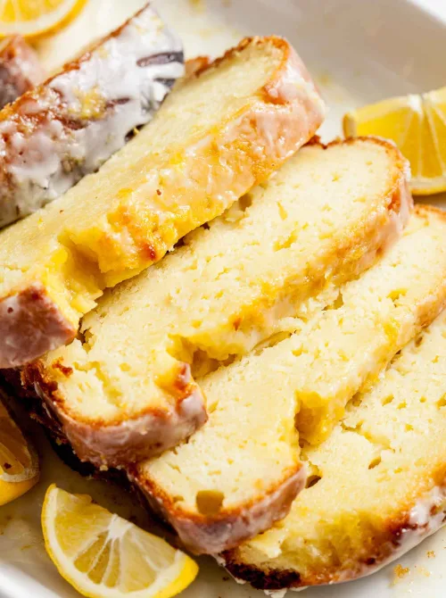 Slices of moist, glazed lemon loaf cake arranged with fresh lemon slices, perfect for a budget-friendly Easter brunch.