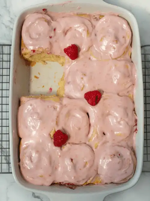 Freshly baked raspberry sweet rolls covered in creamy pink frosting and topped with whole raspberries, perfect for a budget-friendly Easter brunch.
