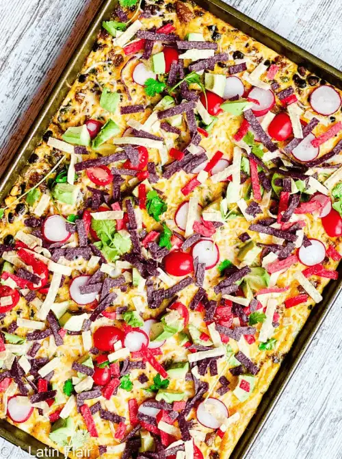 Colorful sheet pan breakfast nachos loaded with eggs, cheese, avocado, tomatoes, radishes, and crispy tortilla strips—an eye-catching and festive option for a budget-friendly Easter brunch.