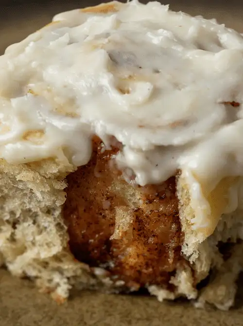 Close-up of a fluffy cinnamon roll generously topped with creamy icing, ideal for a budget-friendly Easter brunch.