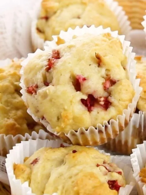 Freshly baked strawberry muffins in white liners, bursting with juicy strawberries, perfect for a budget-friendly Easter brunch.