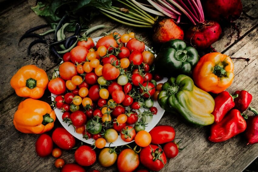 close up shot of tomatoes and peppers on a wooden surface