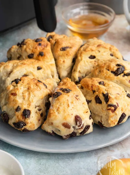 Golden raisin scones arranged in a circle on a blue plate, ready to be served with honey—simple, comforting, and perfect for classic Mother's Day tea party ideas.