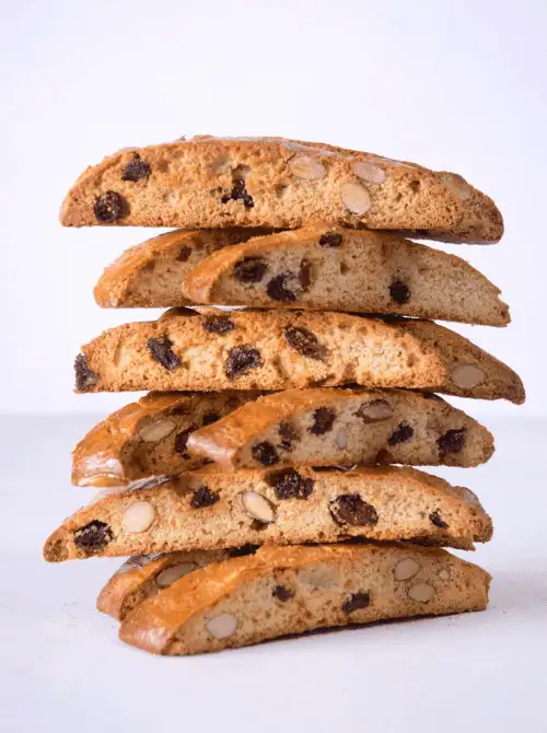 Stack of golden-brown biscotti filled with almonds and raisins, offering a crisp, elegant treat perfect for pairing with tea—ideal for refined and cozy Mother's Day tea party ideas.