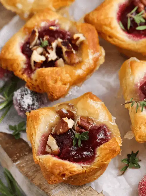 Golden puff pastry bites filled with melted brie, cranberry sauce, and chopped pecans, garnished with fresh herbs—an elegant and savory addition to your Mother's Day tea party ideas.