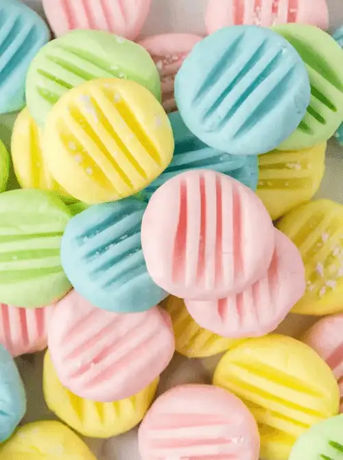 Colorful pastel cream cheese mints in pink, yellow, green, and blue with fork-pressed tops—a sweet and nostalgic treat to brighten up your Mother's Day tea party ideas.