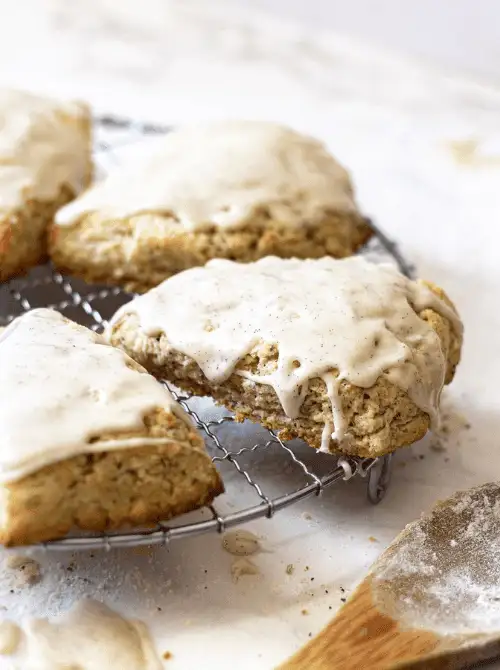 Freshly baked vanilla-glazed scones cooling on a wire rack, with a rustic dusting of flour—an inviting homemade treat perfect for your Mother's Day tea party ideas.