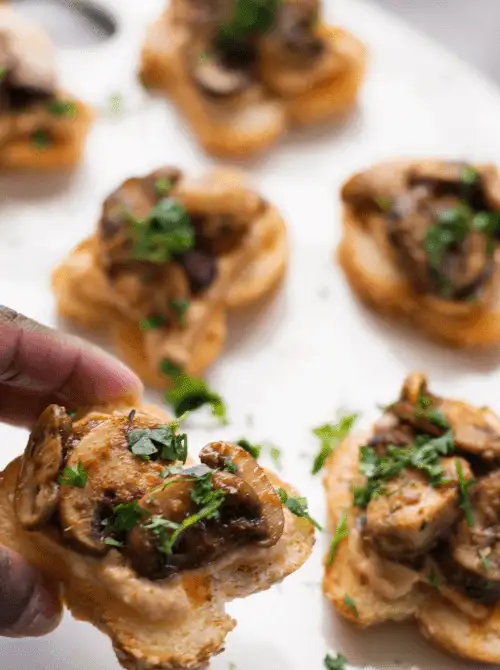 Golden crostini topped with sautéed mushrooms and fresh herbs, arranged on a white platter—these savory bites bring a touch of rustic elegance to your Mother's Day tea party ideas.