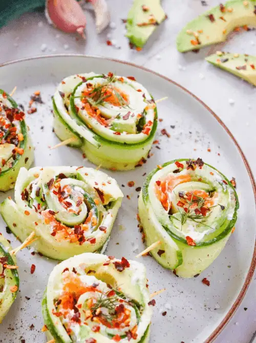 These refreshing cucumber roll-ups, filled with cream cheese, smoked salmon, and avocado, then topped with fresh herbs and red pepper flakes, make a light, elegant, and flavor-packed appetizer for your Mother's Day tea party ideas.