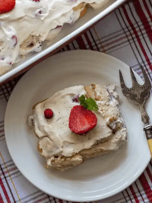 A slice of no-bake strawberry tiramisu served on a white plate, topped with fresh strawberries and mint—an easy 4th of July dessert that’s creamy, fruity, and perfect for summer gatherings.
