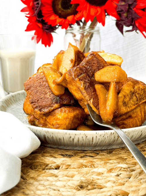 Thick slices of French toast topped with warm, caramelized apples on a rustic plate—an indulgent breakfast option that’s perfect for easy fall recipes and cozy things to make with apples.
