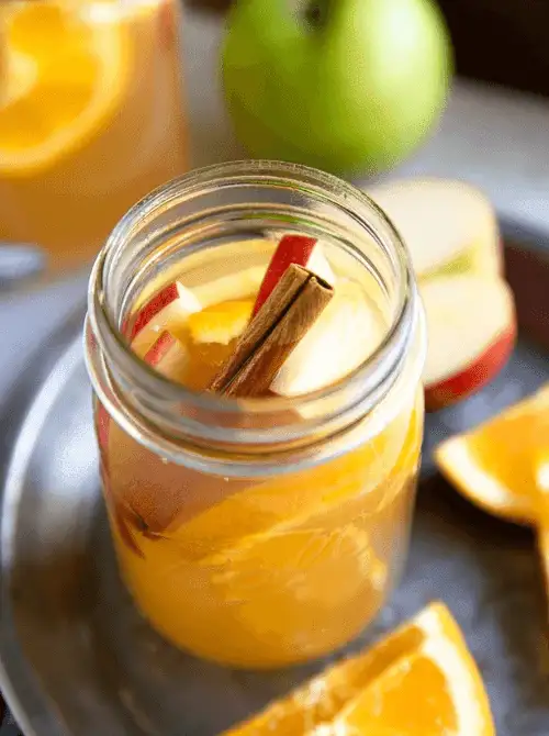 Refreshing apple cider mocktail in a mason jar with sliced apples, oranges, and a cinnamon stick—festive, fruity, and one of the easiest things to make with apples for kid-friendly fall recipes and holiday gatherings.
