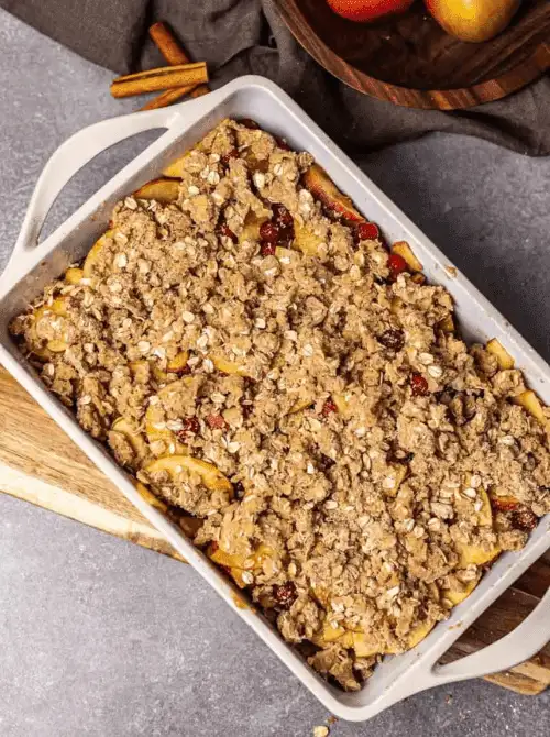 Baked apple cranberry crisp topped with golden oat crumble in a white casserole dish—one of the easiest fall desserts and a cozy, crowd-pleasing thing to make with apples.