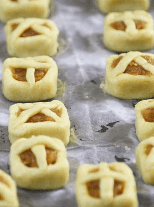 Mini apple pie cookies with lattice crusts on a baking sheet – bite-sized, simple fall treats and one of the cutest things to make with apples for autumn.
