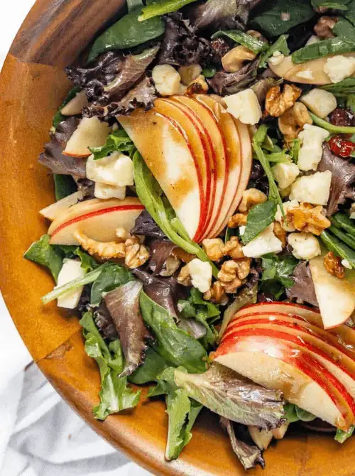 Harvest salad with fresh apple slices, mixed greens, walnuts, dried cranberries, and crumbled cheese tossed in vinaigrette—a crisp and satisfying option for easy fall recipes and flavorful things to make with apples.