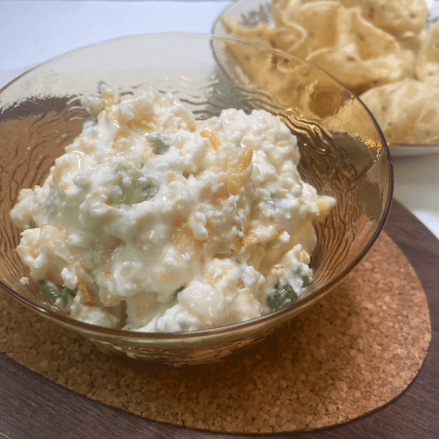 Close-up of creamy Apricot Jalapeño Popper Dip in a glass bowl, served with corn chips for dipping—perfect for parties, tailgates, or game day snacks.