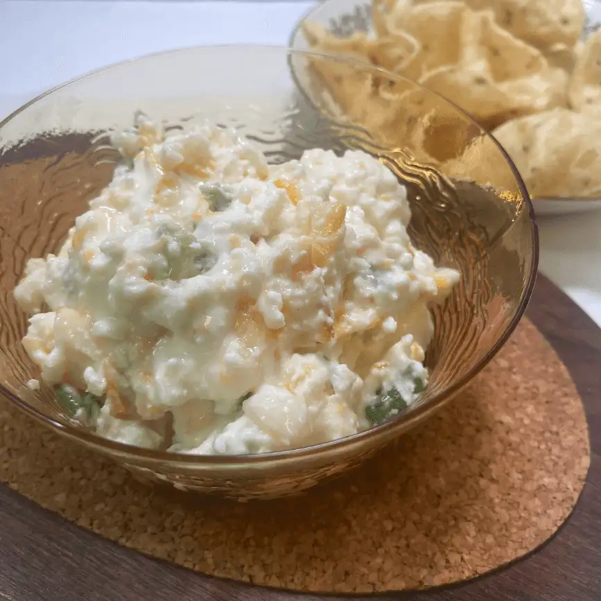Close-up of creamy Apricot Jalapeño Popper Dip in a glass bowl, served with corn chips for dipping—perfect for parties, tailgates, or game day snacks.