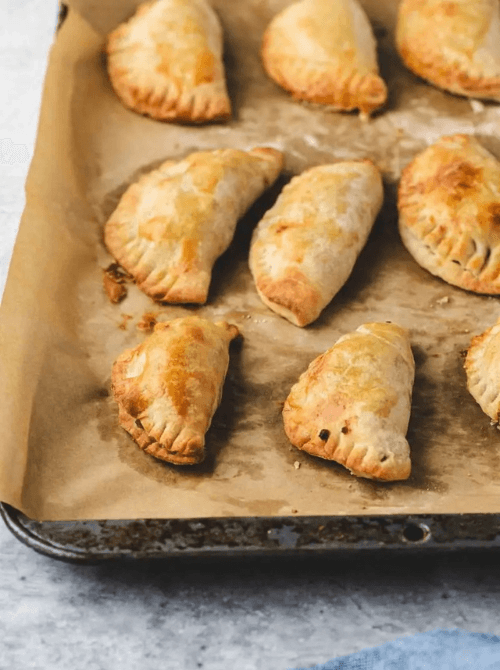 Golden baked apple hand pies on a parchment-lined tray – one of the best simple fall treats and cozy things to make with apples at home.