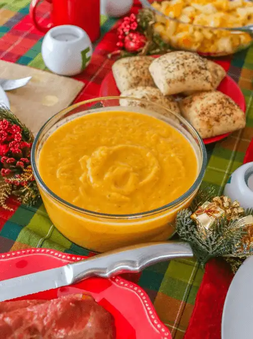 Creamy butternut squash and apple soup served in a glass bowl on a festive fall table—comforting, wholesome, and a cozy choice when looking for easy fall recipes and nourishing things to make with apples.