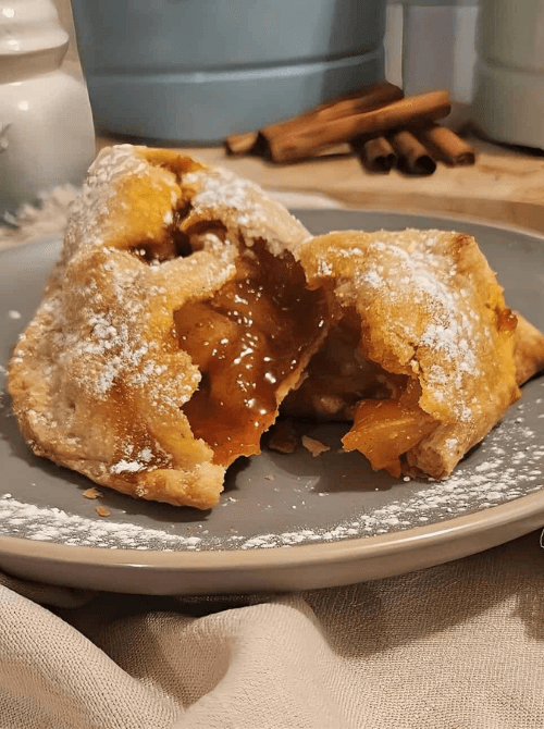 Warm baked apple dumpling with golden crust and gooey cinnamon filling, dusted with powdered sugar – a cozy simple fall treat and one of the best things to make with apples.