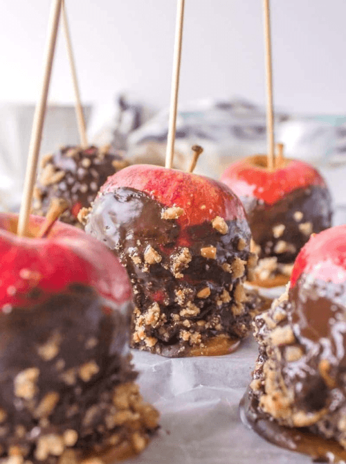 Homemade caramel apples dipped in chocolate and chopped nuts with wooden sticks – a fun and festive thing to make with apples and an easy, simple fall treat for kids and parties.