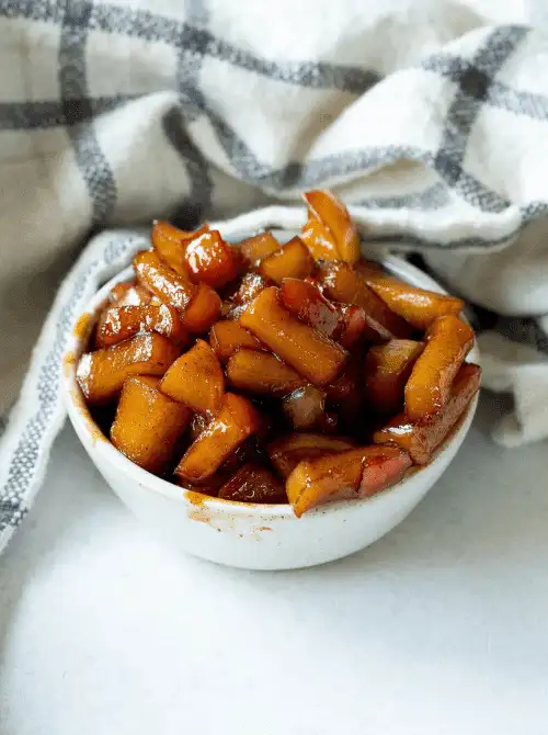 Warm cinnamon-spiced caramelized apples in a small white bowl—sweet, sticky, and one of the coziest things to make with apples for easy fall recipes, perfect as a topping or side.