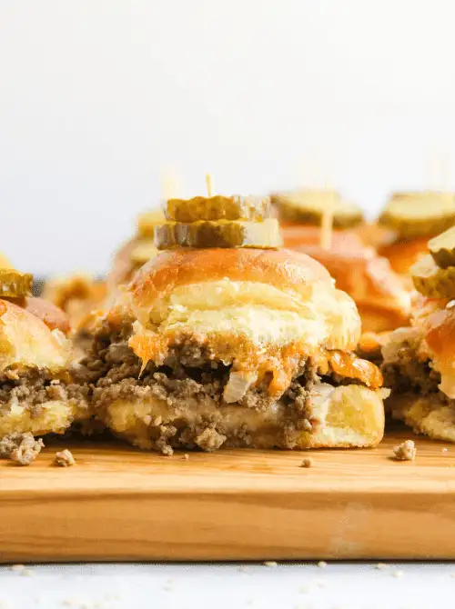 Cheeseburger sliders with ground beef, melted cheese, and pickles on Hawaiian rolls—tailgate food on a budget that’s ideal for serving a hungry crowd.