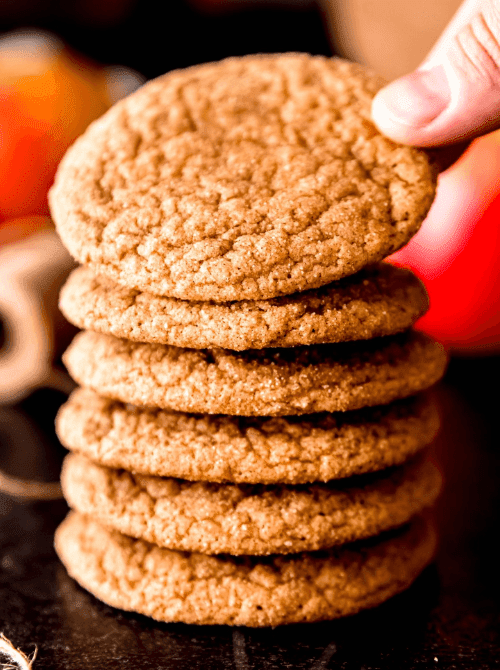 Stack of soft apple spice cookies with a hand reaching for the top – cozy, simple fall treats and one of the easiest things to make with apples for autumn baking.