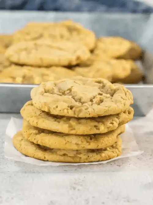 Stack of chewy caramel apple cookies with more cooling in the background – one of the easiest things to make with apples and a deliciously simple fall treat.