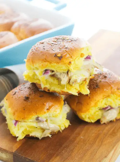 Stacked chicken sliders with red onion and melted cheese on golden slider buns—budget-friendly tailgate food that's easy to prep and perfect for feeding a crowd.