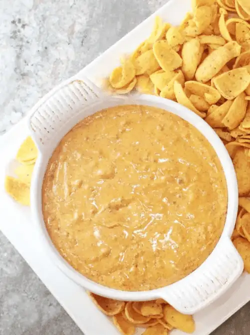 A bowl of warm, cheesy chili dip surrounded by corn chips, perfect for feeding a crowd with easy game day dips.